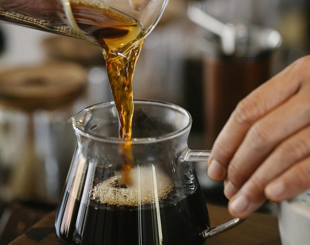 Master the Art: How to Make Coffee Concentrate at Home 20 Crop unrecognizable male barista pouring freshly brewed aromatic coffee from glass measuring pitcher into hot at counter