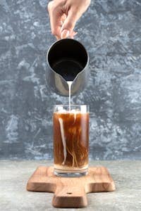 Master the Art: How to Make Coffee Concentrate at Home 23 A Person Pouring Milk to a Glass of Coffee