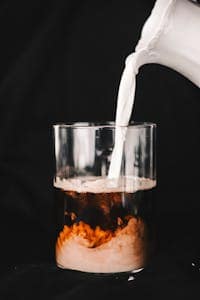 How to Make Cold Brew with French Press: Quick and Easy 6 A person pouring milk into a glass of coffee