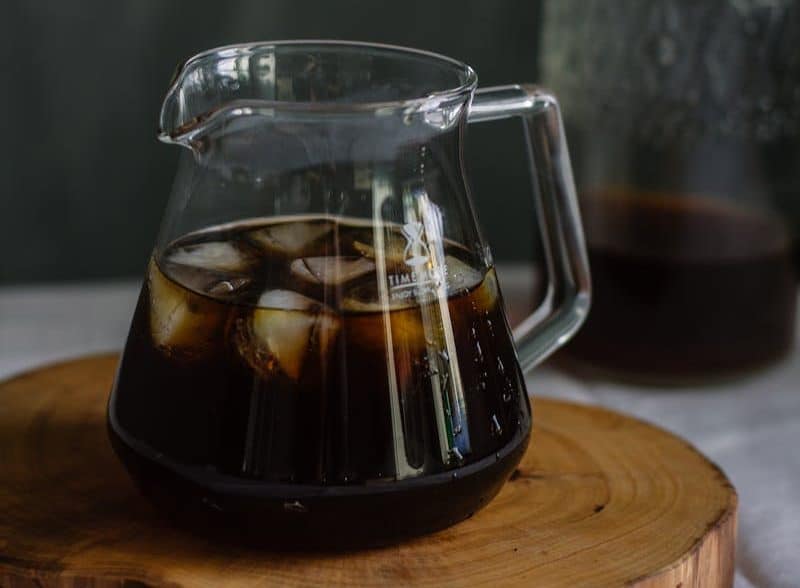 Clear Glass Pitcher With Cola and Ice on Wooden Chopping Board
