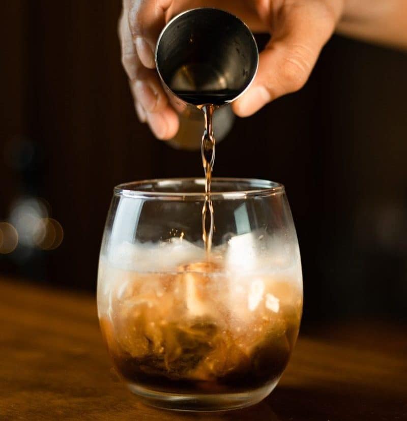a person pours liquid into a glass